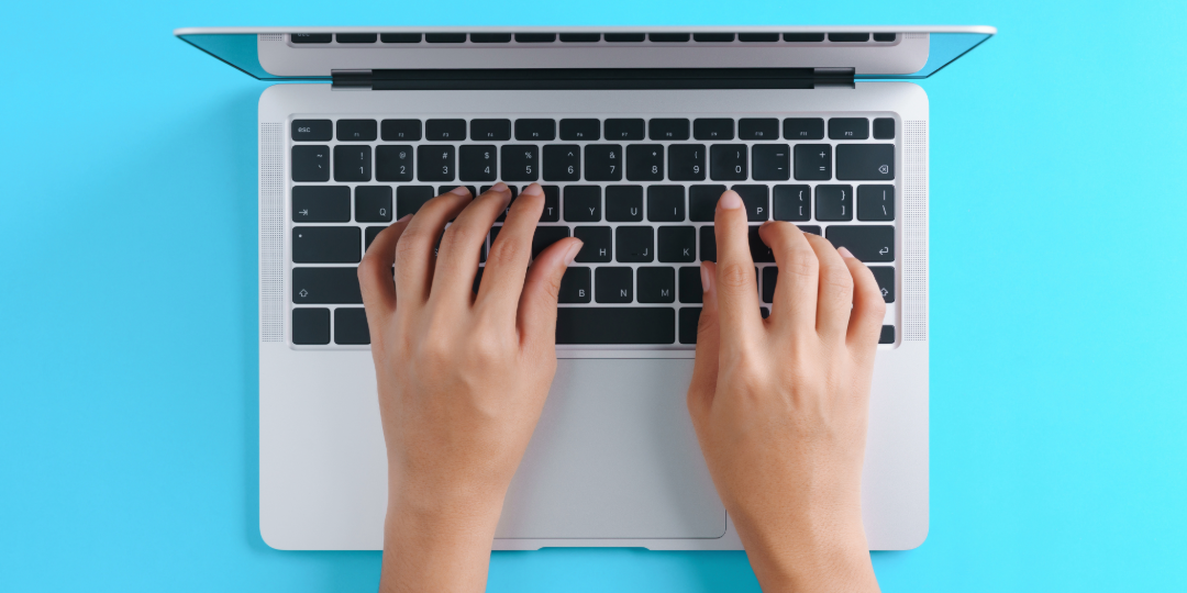 Hands typing on a MacBook. 