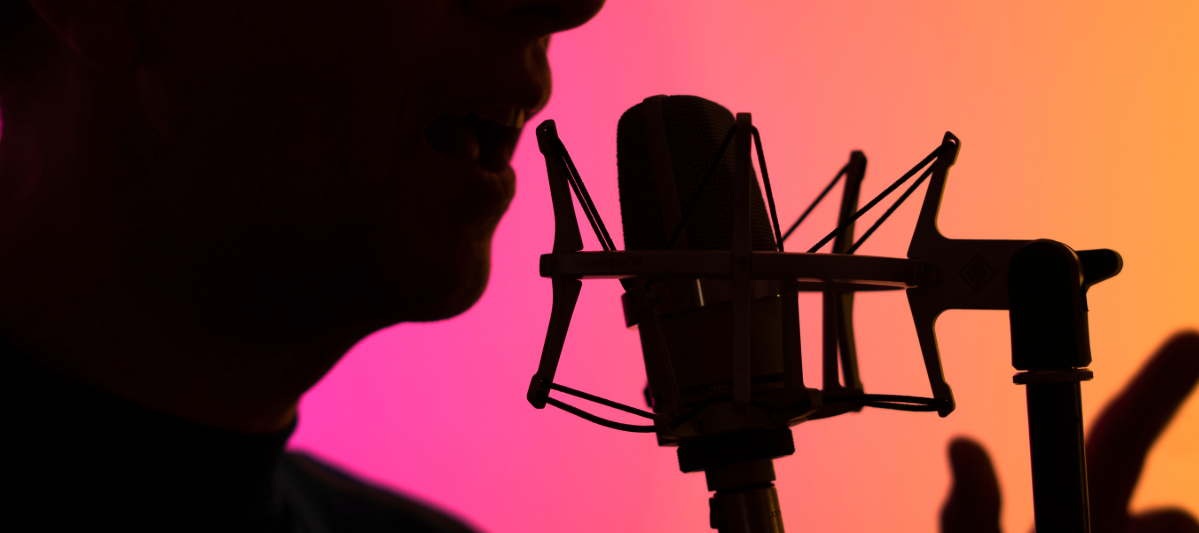 Voice actor over a pink and yellow background in 2024.