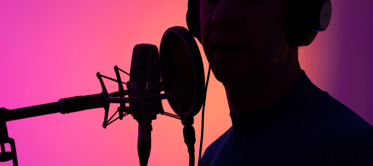 Silhouette of a man learning how to become a voice actor with a pink and orange background. 