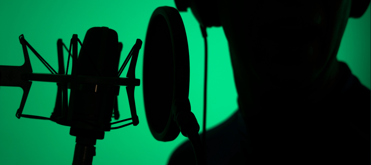 Close-up shot of a voice actor in a green recording studio. 